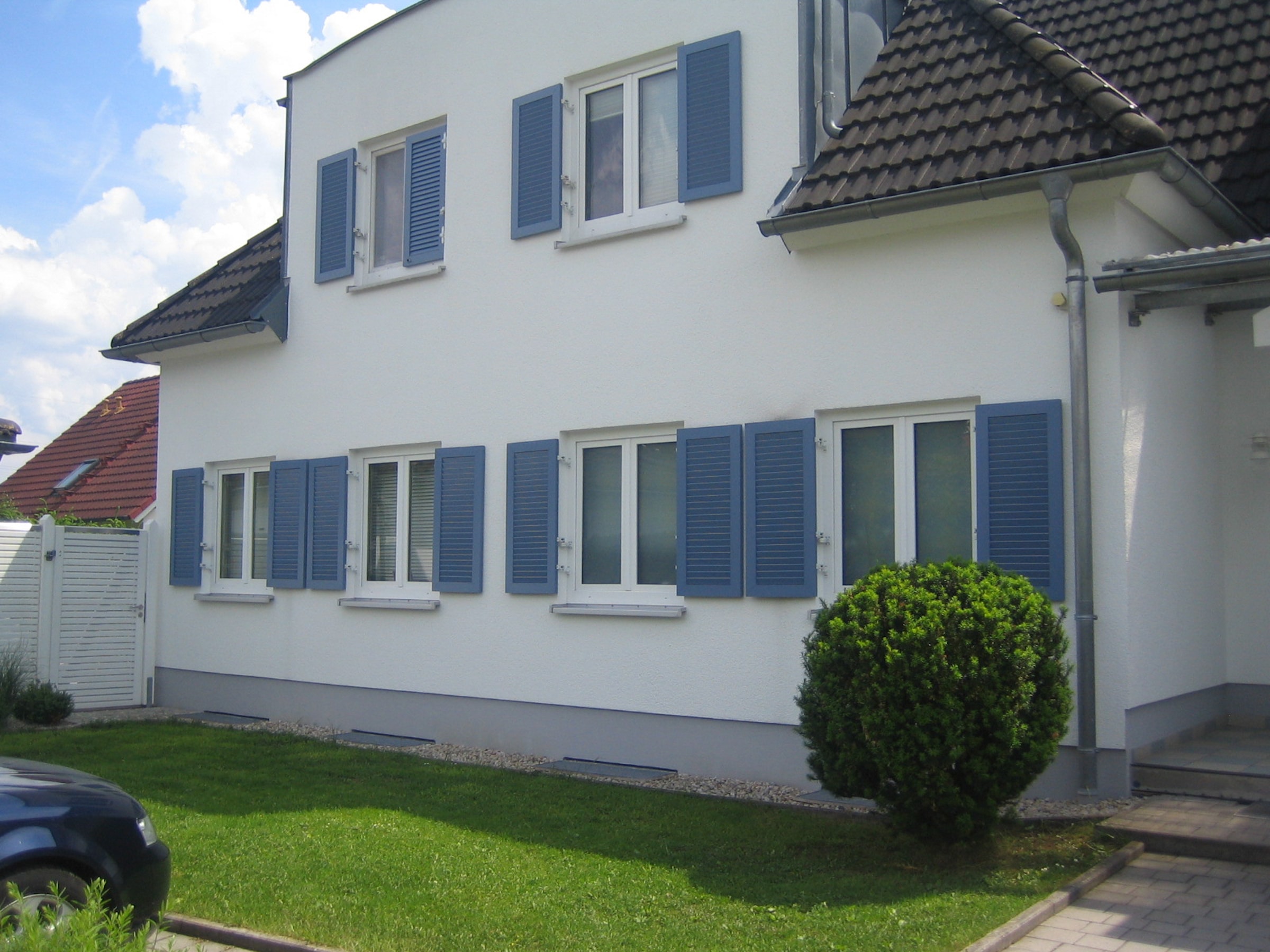 Weiße Hausfassade mit blauen Fensterläden